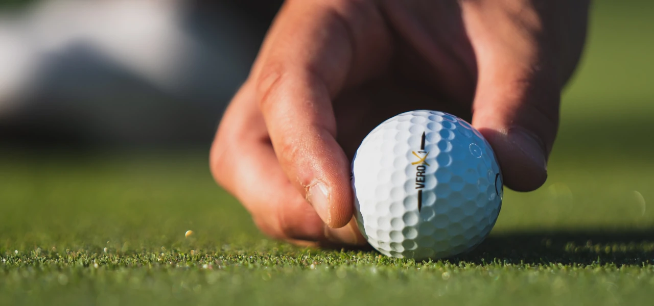 Ein Golfspieler platziert einen Golfball auf dem Green