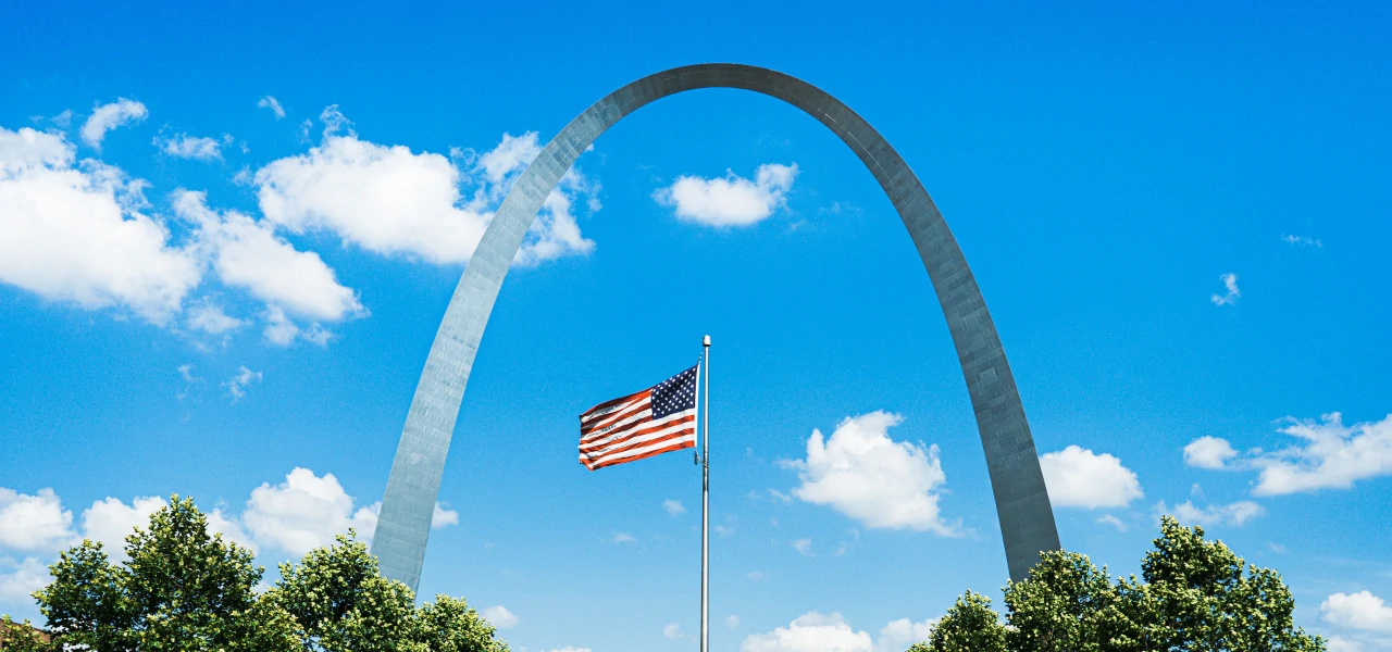Der Gateway Arch in St. Louis Missouri, mit der amerikanischen Flagge im Vordergrund