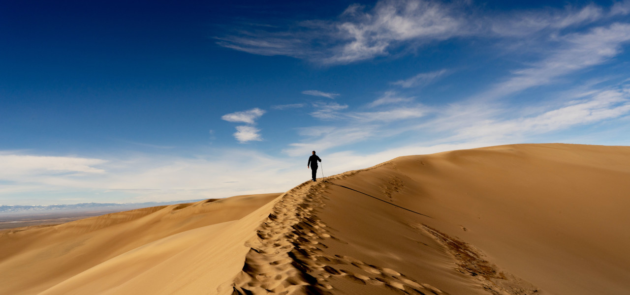 Eine Person wandert über eine große Sanddüne im Great-Sand-Dunes-Nationalpark im US-Bundesstaat Colorado