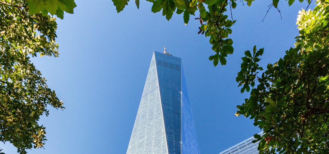 Das One World Trade Center in New York City erstreckt sich vor blauem Himmel in die Lüfte