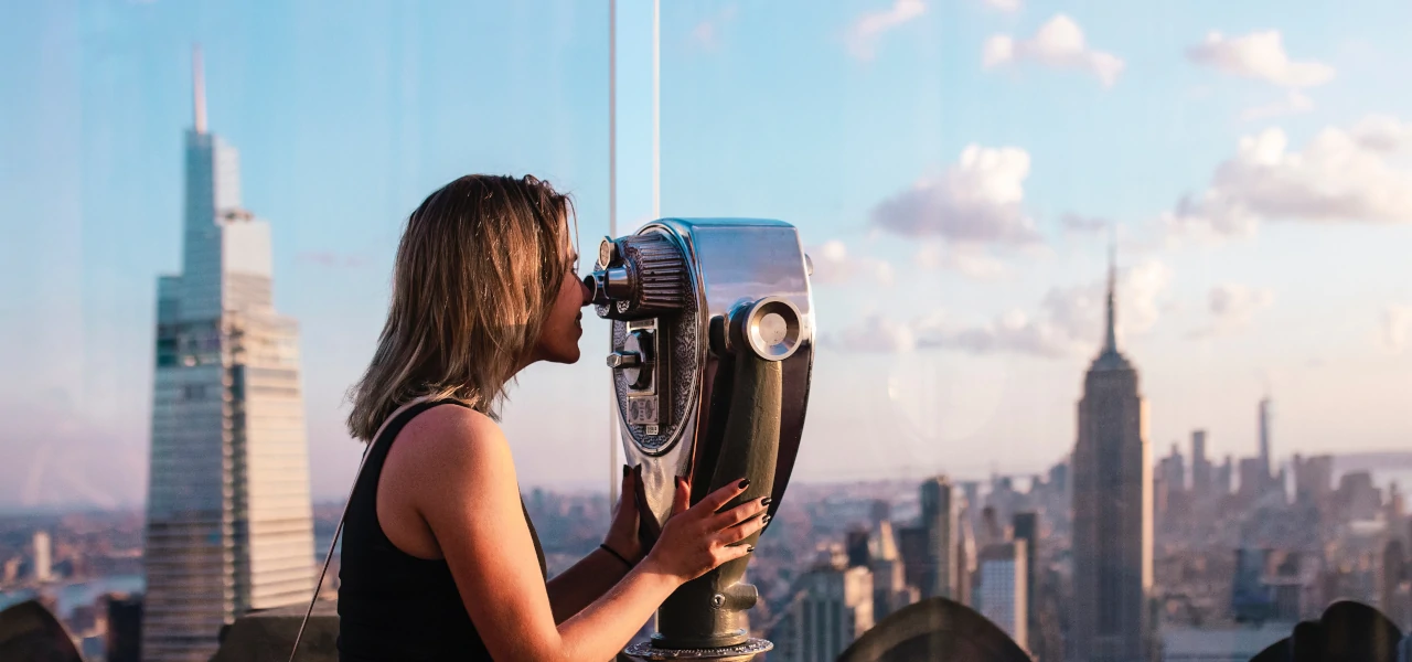 Eine Frau bestaunt New York City durch ein Fernglas auf der Top-of-the-Rock-Aussichtsplattform