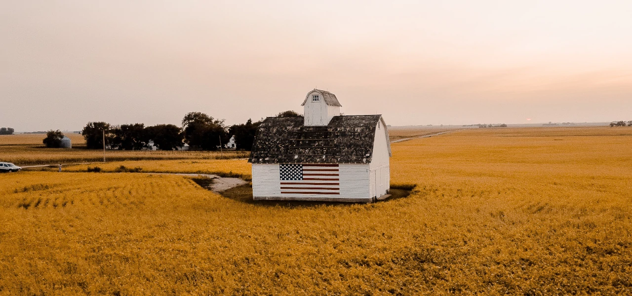 Ein einsames Gebäude mit einer US-Flagge auf der Seite, welches in einem Feld steht