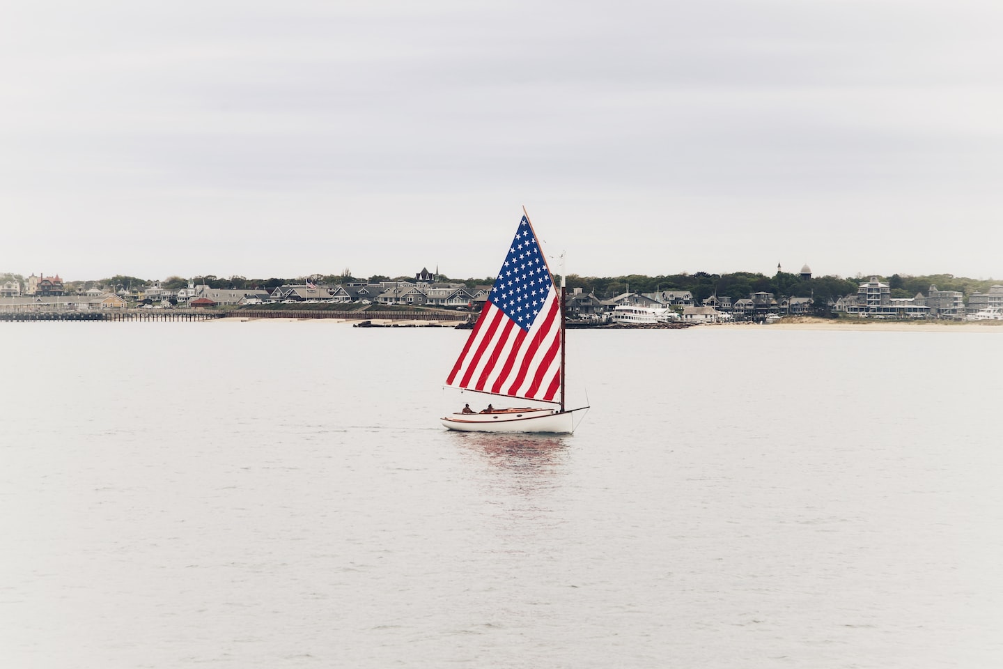 Ein Segelboot, dessen Segel die Farben der US-Amerikanischen Flagge trägt