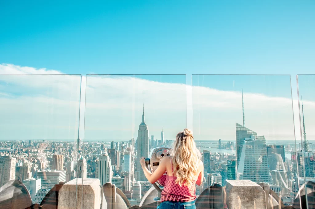Eine Frau beobachtet die Skyline von New York City durch ein Fernglas